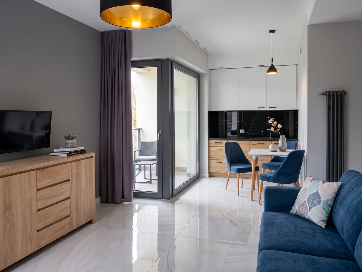 Apartamenty Szmaragdowa 10 — salon z jadalnią, aneksem kuchennym i wyjściem na balkon