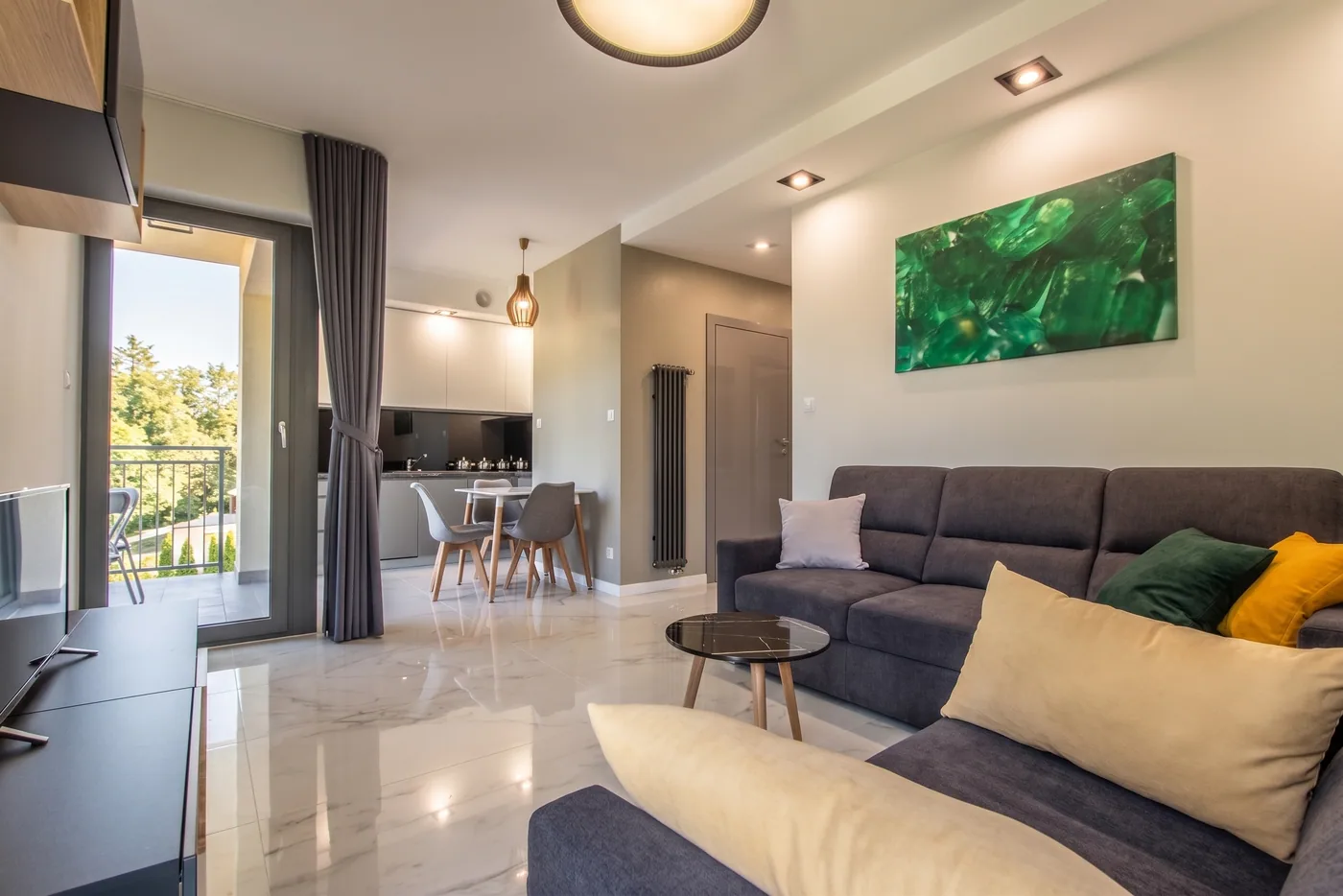Apartamenty Szmaragdowa 10 — przestronny salon z aneksem kuchennym i wyjściem na balkon