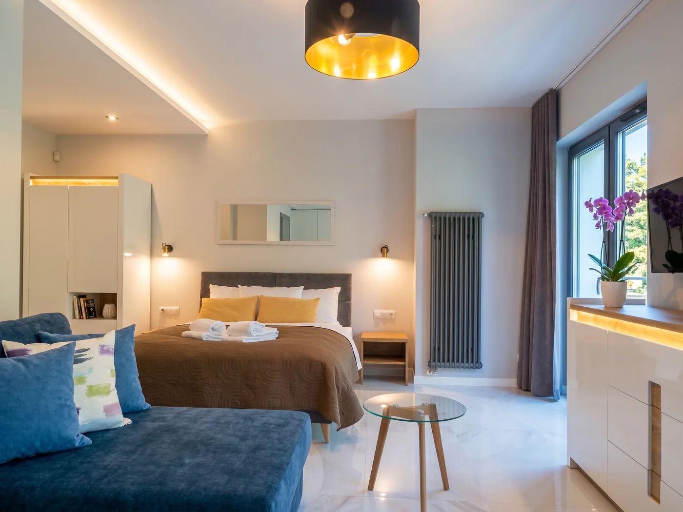 Apartamenty Szmaragdowa 10 — sypialnia z wygodnym łóżkiem i kącikiem wypoczynkowym