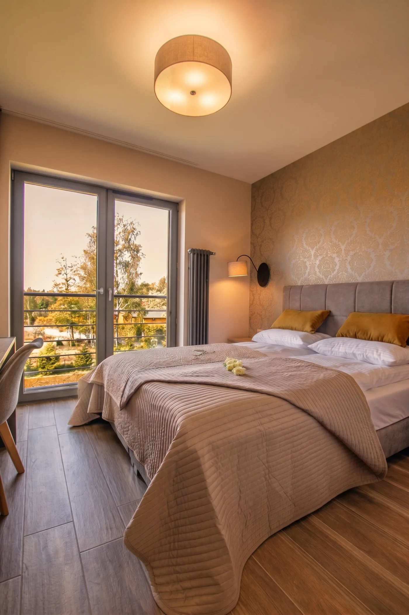 Apartamenty Szmaragdowa 10 — sypialnia z dużym łóżkiem i wyjściem na balkon z widokiem na zieleń