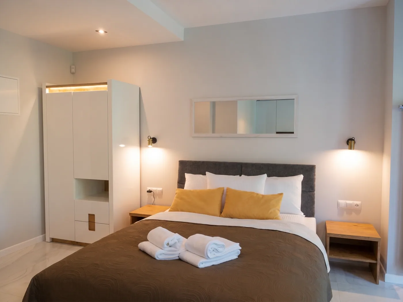 Apartamenty Szmaragdowa 10 — sypialnia z dużym łóżkiem, szafą i lampkami nocnymi