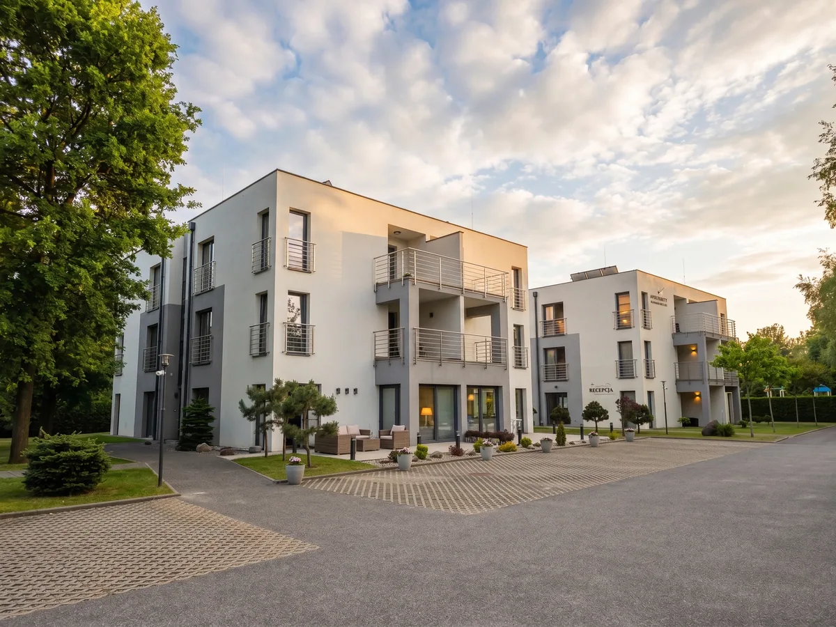 Apartamenty Szmaragdowa 10 — front budynku z recepcją i patio o złotej godzinie